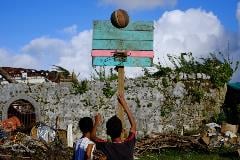 Teenagers playing basketball in devastated location